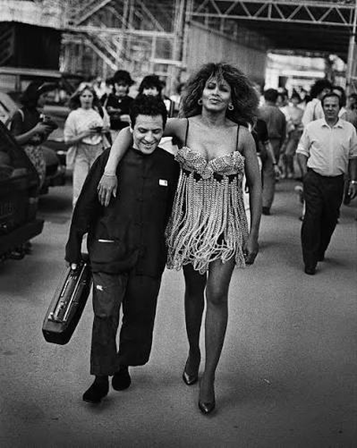 Tina Turner wearing a gold-beaded Azzedine Alaïa dress, walking arm in arm with the designer in Paris, 1989